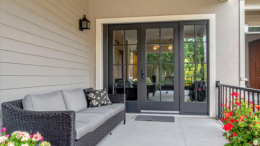 Technician fitting sliding glass patio doors in a modern Aurora, CO family room overlooking a backyard deck